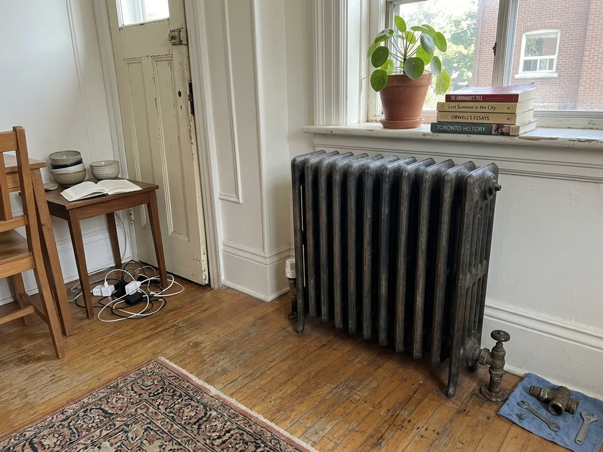 Restored cast iron column radiator with a thermostatic radiator valve in a pre-war Toronto living room